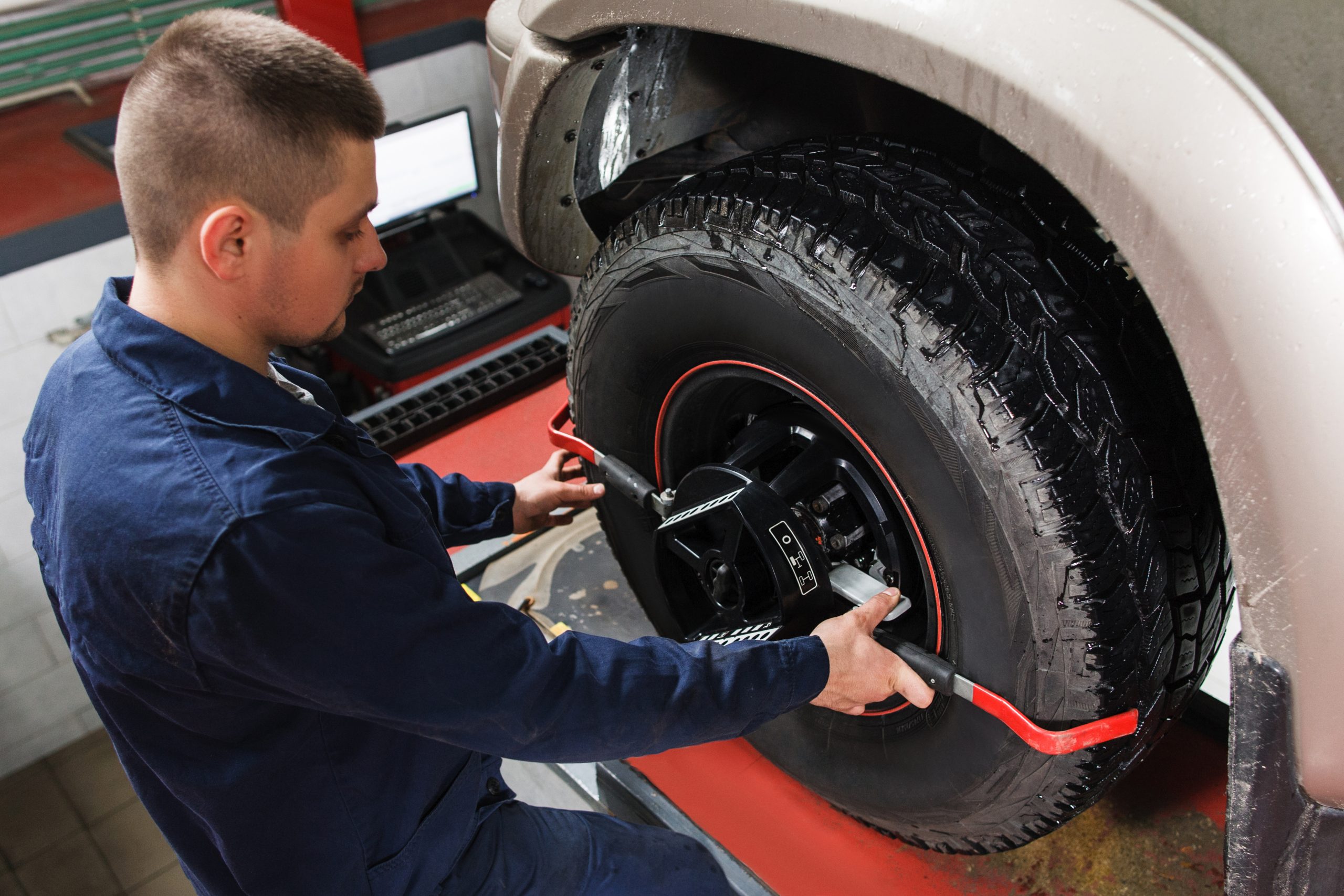 Mechanic adjusting a tire with an alignment tool