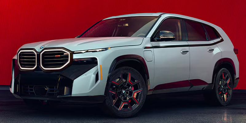 An Alpine White 2025 BMW XM set against a red backdrop