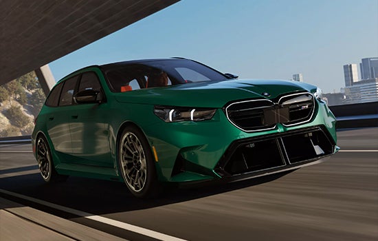 Green BMW M5 Touring driving on a city road. | Tom Bush BMW Jacksonville in Jacksonville FL